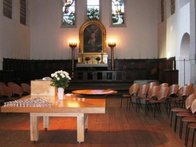 Bord med dåbsfad placeret foran alter med stole rundt omkring.