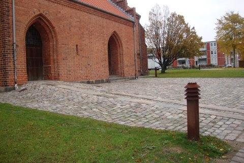 Plads foran kirke med brosten og lang rampe udført i granitsten op til kirkens indgang.